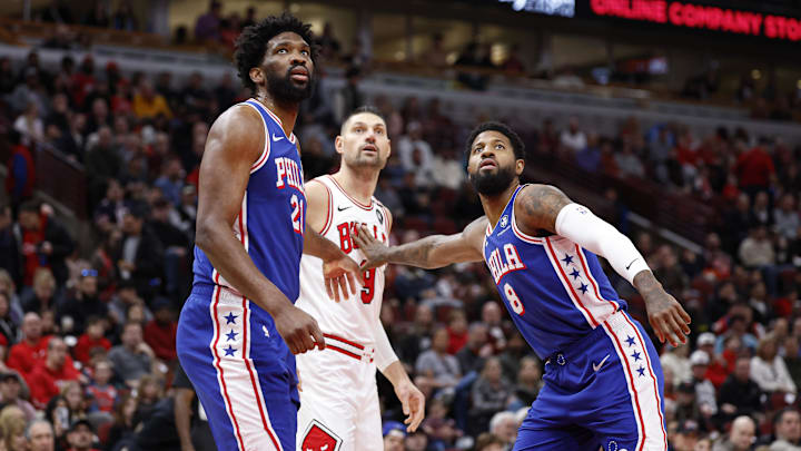 Dec 8, 2024; Chicago, Illinois, USA; Philadelphia 76ers center Joel Embiid (21) and forward Paul George (8) defend against Chicago Bulls center Nikola Vucevic (9) during the first half at United Center. Mandatory Credit: Kamil Krzaczynski-Imagn Images