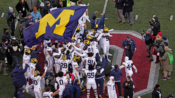 Michigan football players plant their team’s flag at midfield following Saturday’s NCAA Division I football game against the Ohio State Buckeyes at Ohio Stadium. The Michigan Wolverines won the game 13-10.