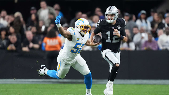Jan 5, 2025; Paradise, Nevada, USA; Las Vegas Raiders quarterback Aidan O'Connell (12) carries the ball against Los Angeles Chargers linebacker Khalil Mack (52) in the second half at Allegiant Stadium. Mandatory Credit: Kirby Lee-Imagn Images