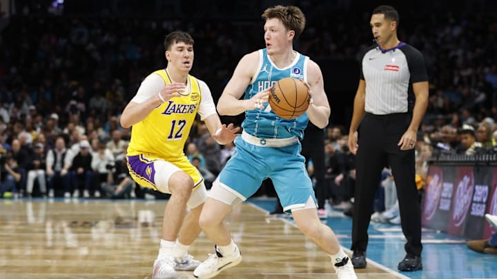 Nov 10, 2025; Charlotte, North Carolina, USA; Charlotte Hornets guard/forward Kon Knueppel (7) is guarded by Los Angeles Lakers forward Jake Laravia (12) during the second half at Spectrum Center. Mandatory Credit: Brian Westerholt-Imagn Images