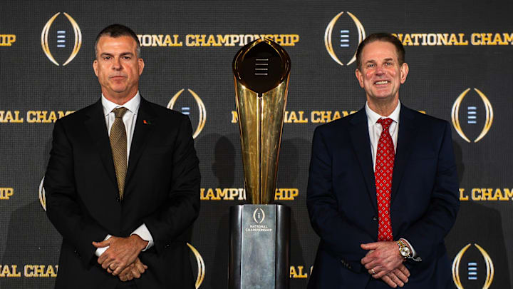 Miami coach Mario Cristobal, left, and Indiana coach Curt Cignetti stand with the national championship trophy ahead of their showdown Monday night.