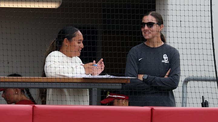 Oklahoma assistants Fale Stelle (left) and Karlie Keeney (right) talk int he dugout at Love's Field.