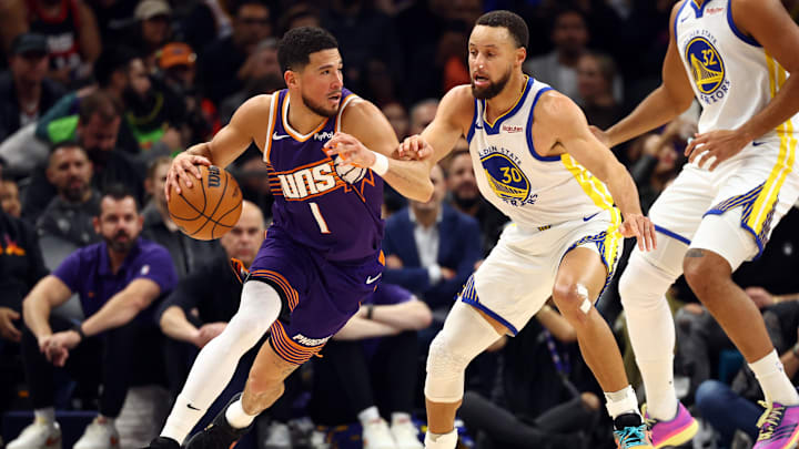 Dec 18, 2025; Phoenix, Arizona, USA; Phoenix Suns guard Devin Booker (1) against Golden State Warriors guard Stephen Curry (30) in the first half at Mortgage Matchup Center. Mandatory Credit: Mark J. Rebilas-Imagn Images