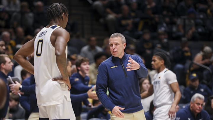 Nov 17, 2025; Morgantown, West Virginia, USA; West Virginia Mountaineers head coach Ross Hodge talks to West Virginia Mountaineers forward Brenen Lorient (0) during the first half against the Lafayette Leopards at WVU Coliseum. Mandatory Credit: Ben Queen-Imagn Images Nov 17, 2025; Morgantown, West Virginia, USA; West Virginia Mountaineers head coach Ross Hodge talks to West Virginia Mountaineers forward Brenen Lorient (0) during the first half against the Lafayette Leopards at WVU Coliseum. Mandatory Credit: Ben Queen-Imagn Images