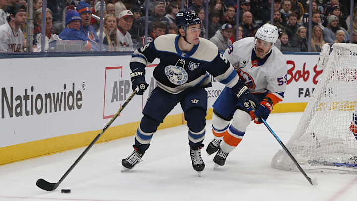 Blue Jackets defenseman Denton Mateychuk looks to make a pass as Islanders forward Casey Czikas pressures him.