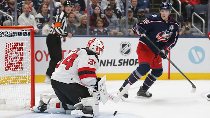 Devils goalie Jake Allen makes a save as Blue Jackets forward Dmitri Voronkov looks on. 
