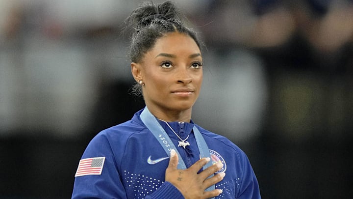 Aug 1, 2024; Paris, France; Simone Biles of the United States during the national anthem after winning the gold medal in the women's gymnastics all-around during the Paris 2024 Olympic Summer Games at Bercy Arena. 