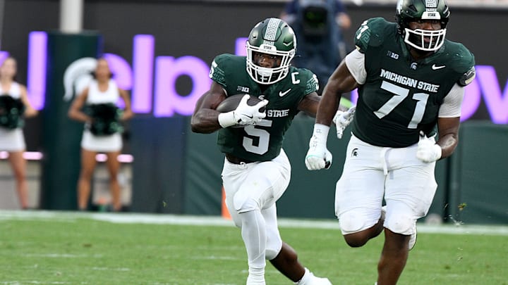 Aug 30, 2024; East Lansing, Michigan, USA;  Michigan State Spartans running back Nate Carter (5) follows blocker Michigan State Spartans offensive lineman Kristian Phillips (71) during the game against the Florida Atlantic Owls at Spartan Stadium. Mandatory Credit: Dale Young-Imagn Images