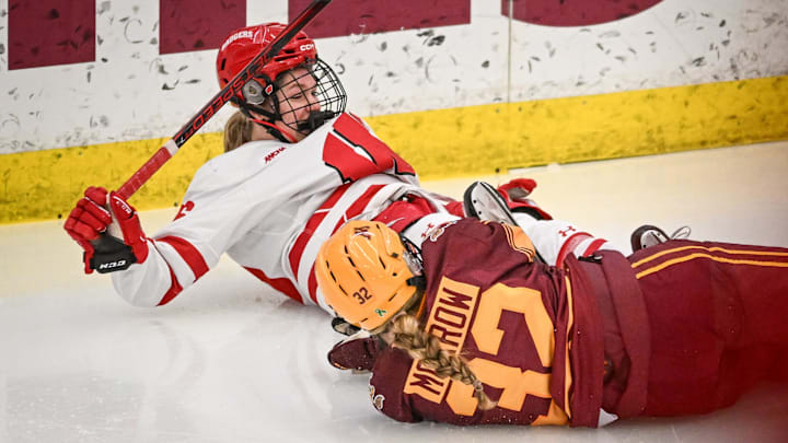 Wisconsin Badgers center Casey O'Brien (26) slides into the boards after being tripped on a breakaway by Minnesota Gophers defender Sydney Morrow (32) in the second period of a game Sunday, February 9, 2025, at LaBahn Arena in Madison, Wisconsin.