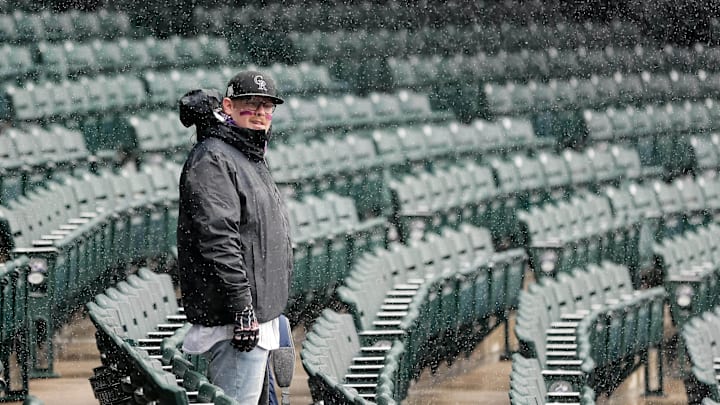 Denver, CO, USA; A Colorado Rockies fans stands as snow falls before a game against the Atlanta Braves at Coors Field.