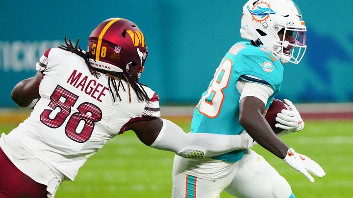 Nov 16, 2025; Madrid, Spain; Miami Dolphins running back De'Von Achane (28) carries the ball and is tackled by Washington Commanders linebacker Jordan Magee (58) in the second quarter during the 2025 NFL Madrid Game at Santiago Bernabeu Stadium. Mandatory Credit: Kirby Lee-Imagn Images