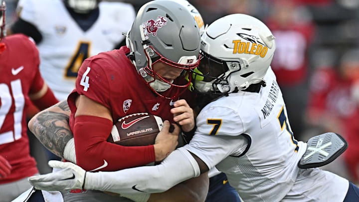 Oct 25, 2025; Pullman, Washington, USA; Washington State Cougars quarterback Zevi Eckhaus (4) is tackled by Toledo Rockets safety Emmanuel McNeil-Warren (7) in the second half at Gesa Field at Martin Stadium. Mandatory Credit: James Snook-Imagn Images
