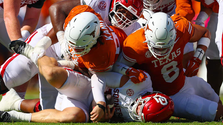 Texas Longhorns defensive lineman Hero Kanu and Texas Longhorns linebacker Trey Moore tackle Oklahoma Sooners quarterback John Mateer during the first half at the Cotton Bowl.