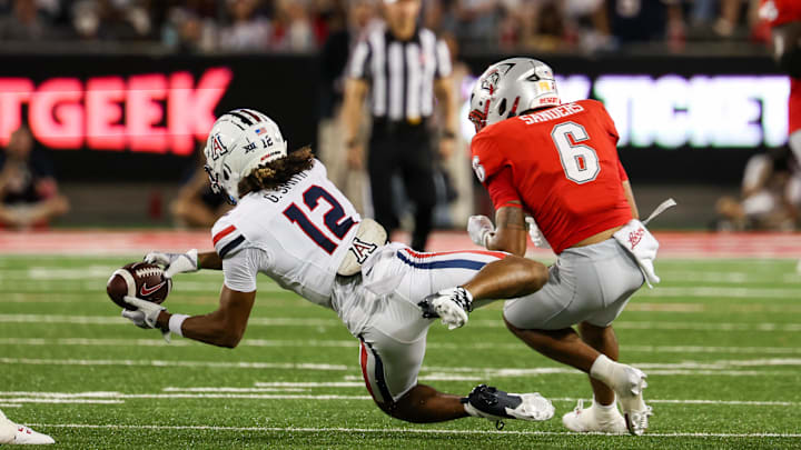 Aug 31, 2024; Tucson, Arizona, USA; Arizona Wildcats defensive back Genesis Smith (12) intercepts ball from New Mexico Lobos running back Eli Sanders (6) during second quarter at Arizona Stadium. Mandatory Credit: Aryanna Frank-Imagn Images