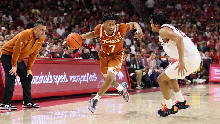 Mar 4, 2026; Fayetteville, Arkansas, USA; Texas Longhorns guard Simeon Wilcher (7) drives against Arkansas Razorbacks guard D.J. Wagner (24) during the second half as Longhorns head coach Sean Miller looks on at Bud Walton Arena. Mandatory Credit: Nelson Chenault-Imagn Images