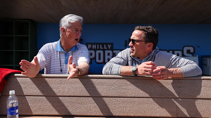 Feb 25, 2024; Clearwater, Florida, USA;  Philadelphia Phillies president of baseball operations Dave Dombrowski and general manager Sam Fuld talk in the dugout before a game against the New York Yankees at BayCare Ballpark.