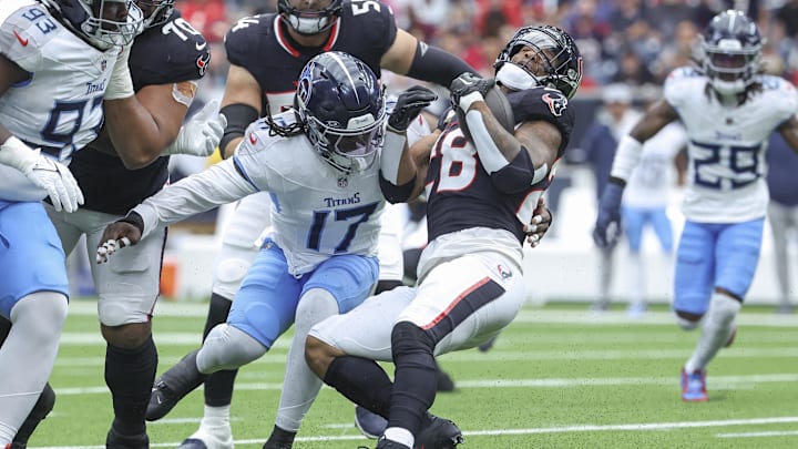 Nov 24, 2024; Houston, Texas, USA; Houston Texans running back Joe Mixon (28) runs with the ball as Tennessee Titans linebacker Jerome Baker (17) attempts to make a tackle during the first quarter at NRG Stadium. Mandatory Credit: Troy Taormina-Imagn Images