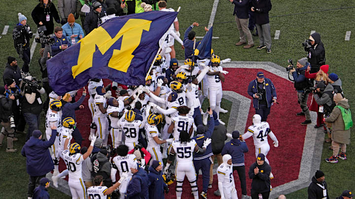 Michigan football players plant their team’s flag at midfield following Saturday’s NCAA Division I football game against the Ohio State Buckeyes at Ohio Stadium. The Michigan Wolverines won the game 13-10.