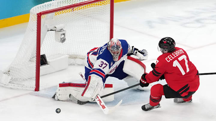 Feb 22, 2026; Milan, Italy; Connor Hellebuyck of the United States battles for the puck against Macklin Celebrini of Canada during the men's ice hockey gold medal game during the Milano Cortina 2026 Olympic Winter Games at Milano Santagiulia Ice Hockey Arena. Mandatory Credit: James Lang-Imagn Images