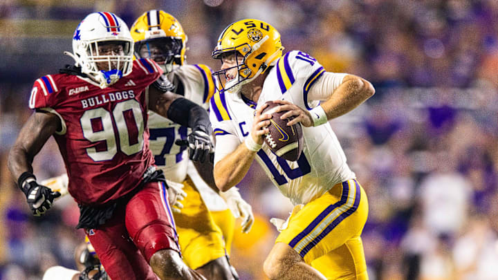Sep 6, 2025; Baton Rouge, Louisiana, USA;  LSU Tigers quarterback Garrett Nussmeier (18) scrambles out the pocket against Louisiana Tech Bulldogs defensive lineman Jayden Madkins (90) during the second half  at Tiger Stadium. Mandatory Credit: Stephen Lew-Imagn Images