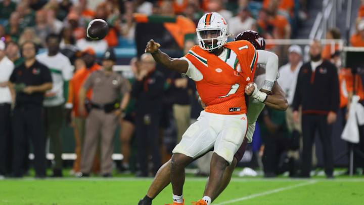 Sep 27, 2024; Miami Gardens, Florida, USA; Miami Hurricanes quarterback Cam Ward (1) throws the football as Virginia Tech Hokies defensive lineman Wilfried Pene (91) attempts a tackle during the second quarter at Hard Rock Stadium. Mandatory Credit: Sam Navarro-Imagn Images