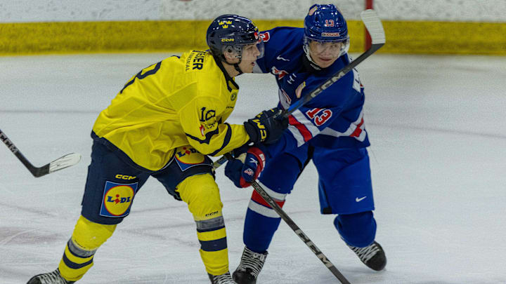 Aug 2, 2024; Plymouth, MI, USA; USA’s defenceman Lukas Fischer (13) battles for position with Sweden's forward Victor Eklund (18) during the first period of the 2024 World Junior Summer Showcase at USA Hockey Arena. Mandatory Credit: David Reginek-Imagn Images