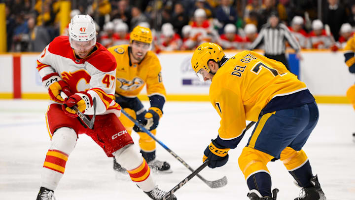 Dec 10, 2024; Nashville, Tennessee, USA;  Calgary Flames center Connor Zary (47) and Nashville Predators defenseman Marc Del Gaizo (7) battle for the puck during the second period at Bridgestone Arena. Mandatory Credit: Steve Roberts-Imagn Images