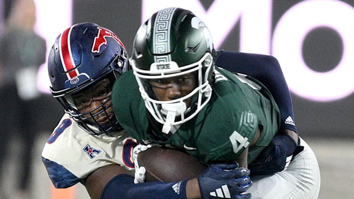 Aug 30, 2024; East Lansing, Michigan, USA;  Michigan State Spartans wide receiver Jaron Glover (4) gets wrapped up by Florida Atlantic Owls cornerback Logic Hudgens (8) in the third quarter at Spartan Stadium. Mandatory Credit: Dale Young-Imagn Images