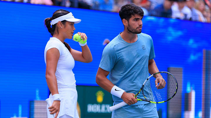 August 19, 2025; Emma Raducanu and Carlos Alcaraz talk strategy during a mixed doubles match against Jessica Pegula and Jack Draper at the 2025 US Open at USTA Billie Jean King National Tennis Center.