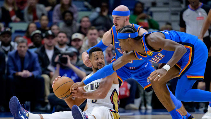 Dec 7, 2024; New Orleans, Louisiana, USA; Oklahoma City Thunder guard Shai Gilgeous-Alexander (2) and guard Alex Caruso (9) battle New Orleans Pelicans guard CJ McCollum (3) for the ball during the first half at Smoothie King Center. Mandatory Credit: Matthew Hinton-Imagn Images