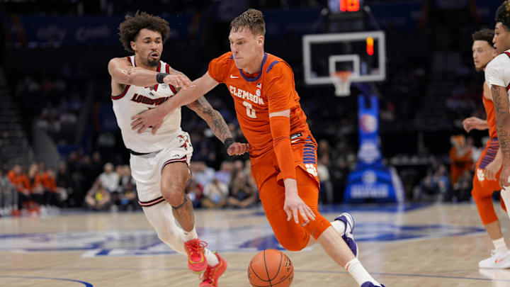 Mar 14, 2025; Charlotte, NC, USA; Clemson Tigers center Viktor Lakhin (0) drives to the basket against Louisville Cardinals guard J'Vonne Hadley (1)  during the first half at Spectrum Center. Mandatory Credit: Jim Dedmon-Imagn Images