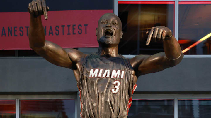 Oct 28, 2024; Miami, Florida, USA;  Former Miami Heat guard Dwyane Wade poses with his statue in front of the Kaseya Center. Mandatory Credit: Rhona Wise-Imagn Images