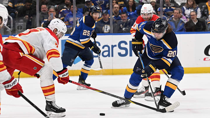 Jan 14, 2025; St. Louis, Missouri, USA; Calgary Flames defenseman Kevin Bahl (7) battles St. Louis Blues left wing Brandon Saad (20) for the puck in the second period at Enterprise Center. Mandatory Credit: Joe Puetz-Imagn Images