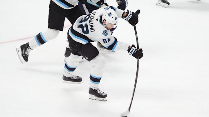 Dec 12, 2024; Denver, Colorado, USA; Utah Hockey Club center Kevin Stenlund (82) shoots and scores an empty net goal in the third period against the Colorado Avalanche at Ball Arena. Mandatory Credit: Ron Chenoy-Imagn Images