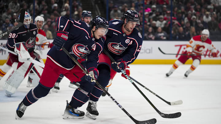 Nov 29, 2024; Columbus, Ohio, USA;  Columbus Blue Jackets defenseman Zach Werenski (8) skates with the puck alongside center Sean Monahan (23) in the game against the Calgary Flames in the third period at Nationwide Arena. Mandatory Credit: Aaron Doster-Imagn Images