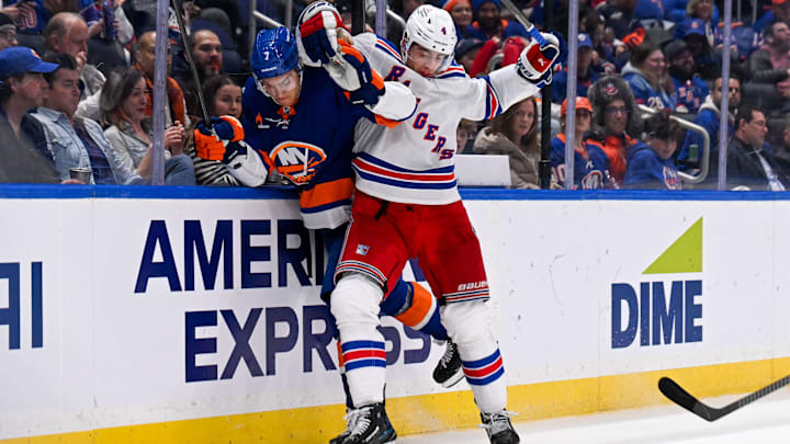 Apr 10, 2025; Elmont, New York, USA;  New York Rangers defenseman Braden Schneider (4) checks New York Islanders right wing Maxim Tsyplakov (7) into the boards during the second period at UBS Arena. Mandatory Credit: Dennis Schneidler-Imagn Images
