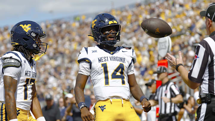 Oct 18, 2025; Orlando, Florida, USA; West Virginia Mountaineers quarterback Khalil Wilkins (14) flexes after scoring a touchdown in the first half against the Central Florida Knights at Acrisure Bounce House. Mandatory Credit: Russell Lansford-Imagn Images