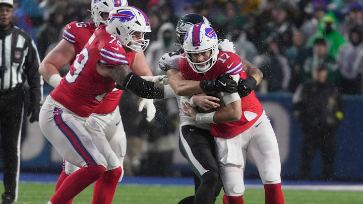 Buffalo Bills quarterback Josh Allen runs with the ball but is wrapped up by Philadelphia Eagles linebacker Zack Baun.