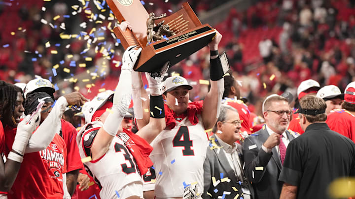 Dec 6, 2025; Atlanta, GA, USA; Georgia Bulldogs tight end Oscar Delp (4) and Georgia Bulldogs running back Cash Jones (32) lift the SEC Championship trophy after the game against the Alabama Crimson Tide during the 2025 SEC Championship game at Mercedes-Benz Stadium. Mandatory Credit: Dale Zanine-Imagn Images Dec 6, 2025; Atlanta, GA, USA; Georgia Bulldogs tight end Oscar Delp (4) and Georgia Bulldogs running back Cash Jones (32) lift the SEC Championship trophy after the game against the Alabama Crimson Tide during the 2025 SEC Championship game at Mercedes-Benz Stadium. Mandatory Credit: Dale Zanine-Imagn Images