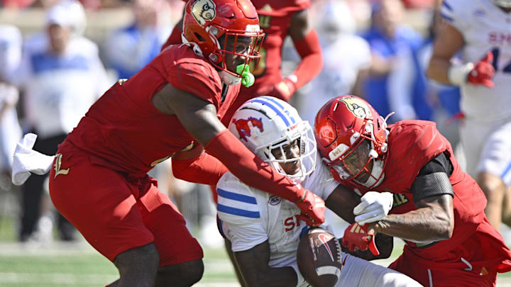 Oct 5, 2024; Louisville, Kentucky, USA;  Louisville Cardinals linebacker Stanquan Clark (6) and defensive back Tamarion McDonald (12) try to strip the ball from Southern Methodist Mustangs running back Brashard Smith (1) during the second half at L&N Federal Credit Union Stadium. Mandatory Credit: Jamie Rhodes-Imagn Images