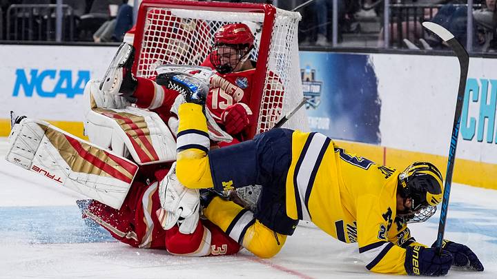 Michigan forward Malcolm Spence (27) falls on Denver goaltender Johnny Hicks (31) during the third period of the Frozen Four semifinal at T-Mobile Arena in Las Vegas on Thursday, April 9, 2026