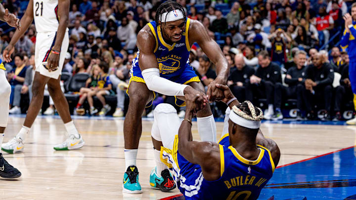 Golden State Warriors guard Buddy Hield (7) picks up forward Jimmy Butler III (10) after a play against the New Orleans Pelicans during the second half at Smoothie King Center. 