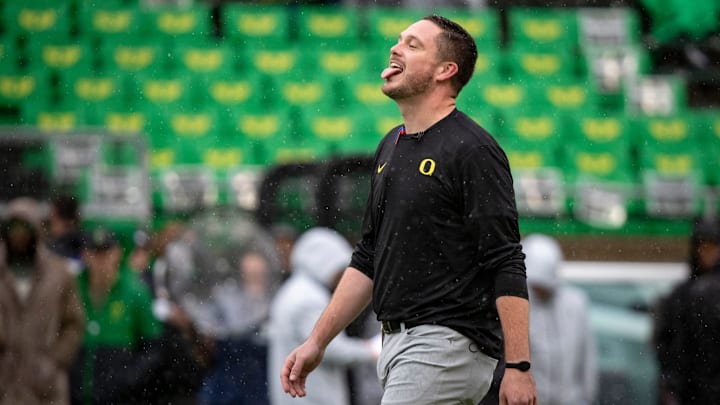 Oregon head coach Dan Lanning sticks his tongue out to catch the rain.