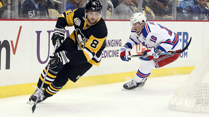 Pittsburgh Penguins defenseman Brian Dumoulin chases the puck ahead of New York Rangers left wing J.T. Miller