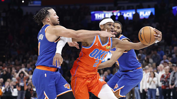 Jan 3, 2025; Oklahoma City, Oklahoma, USA; Oklahoma City Thunder guard Shai Gilgeous-Alexander (2) drives between New York Knicks guard Jalen Brunson (11) and forward Mikal Bridges (25) during the second half at Paycom Center. Mandatory Credit: Alonzo Adams-Imagn Images