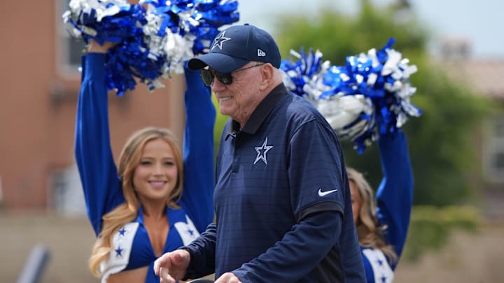 Dallas Cowboys owner Jerry Jones walks past cheerleaders at training camp opening ceremonies at the River Ridge Fields. 