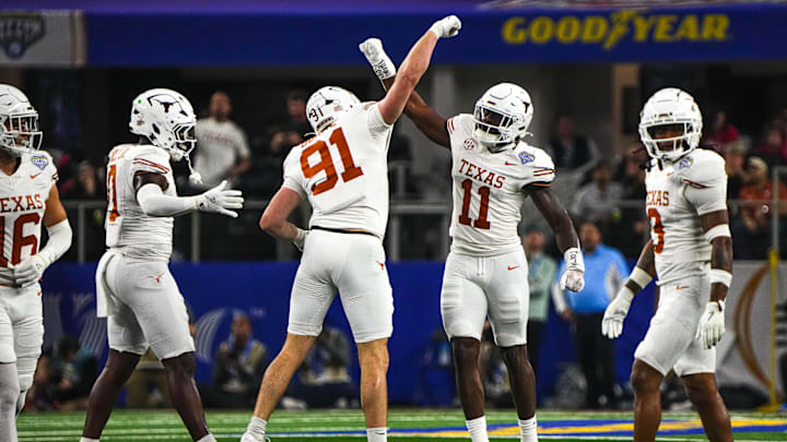 Texas Longhorns edge rushers Colin Simmons (11) and Ethan Burke (91) celebrate a sack during the College Football Playoff semifinal game against Ohio State in the Cotton Bowl at AT&T Stadium on Friday, Jan. 10, 2024 in Arlington, Texas.