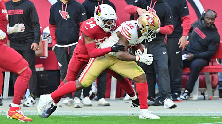Jan 5, 2025; Glendale, Arizona, USA; Arizona Cardinals safety Jalen Thompson (34) tackes San Francisco 49ers running back Patrick Taylor Jr. (32) in the first half at State Farm Stadium. Mandatory Credit: Matt Kartozian-Imagn Images