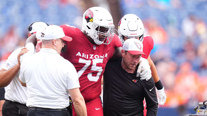 Aug 25, 2024; Denver, Colorado, USA; Arizona Cardinals offensive tackle Christian Jones (75) is helped towards a cart in the second half against the Arizona Cardinals at Empower Field at Mile High. Mandatory Credit: Ron Chenoy-Imagn Images