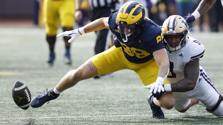 Husky linebacker Jacob Manu separates the ball from Michiga tight end Deakon Tonielli (88).